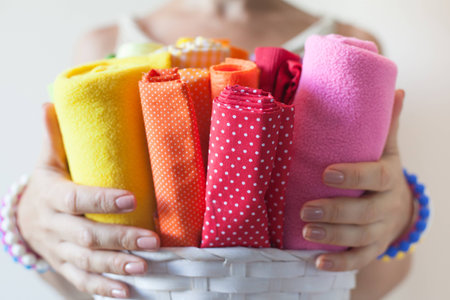 A woman holds bright colored fabrics for sewing and scissors.