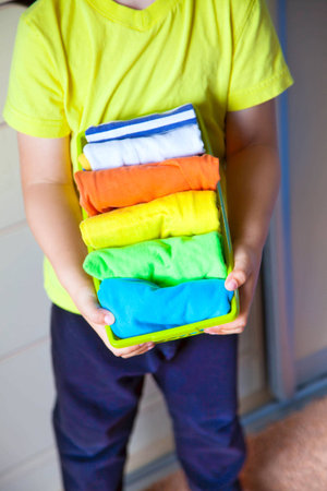 The child keeps his things. The boy puts the T-shirts in a drawer.の写真素材