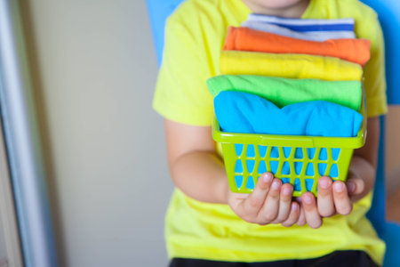 The child keeps his things. The boy puts the T-shirts in a drawer.の写真素材