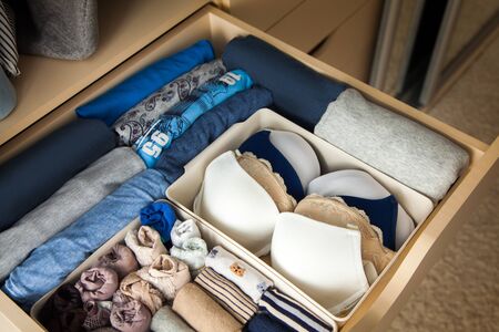 Top view of neatly folded things in grey blue color and accessories are in a drawer in the closet. The concept of perfect tidy and convenient storage of clothesの写真素材