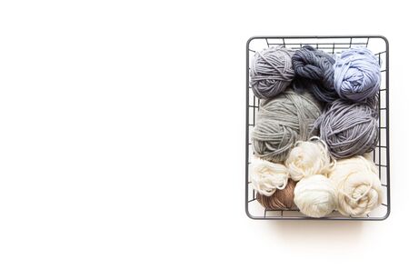 Yarn of gray, white and dark shades in a black metal basket. Knitting needles. Nordic style....