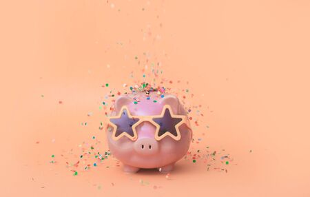 A pink piggy bank in fun glasses at a party. pink background.の写真素材