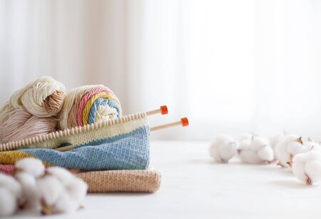 Knitting project in progress. A piece of knitting with ball of yarn and a knitting needles. White wooden background.の写真素材