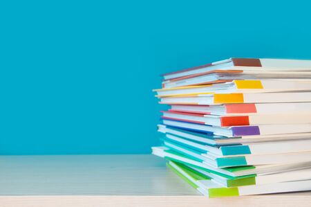 Stack of colorful books on color background.