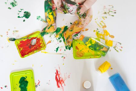 A smiling, funny, cute kid draws hands on the floor and paper.の写真素材