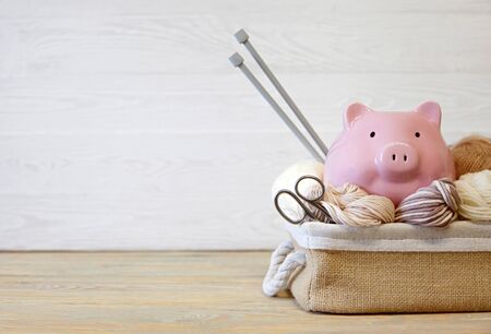 Colored yarn. Knitting needles. Pig piggy bank with glasses. Wooden background.の写真素材