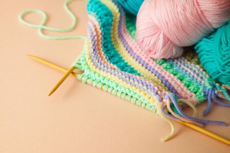 Colored yarn for knitting, knitting needles and scissors. Female hobby concept. Beige background.