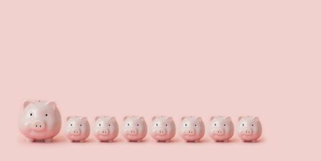 One large piggy bank and seven small ones stand on pink backgroundの写真素材