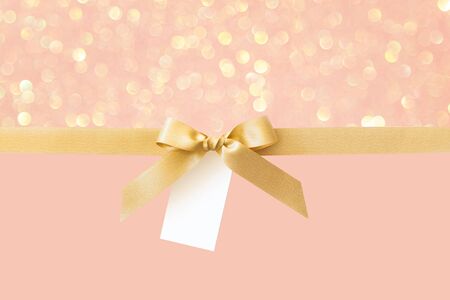 Gold ribbon with a bow as a gift on a pink and gold Shiny background