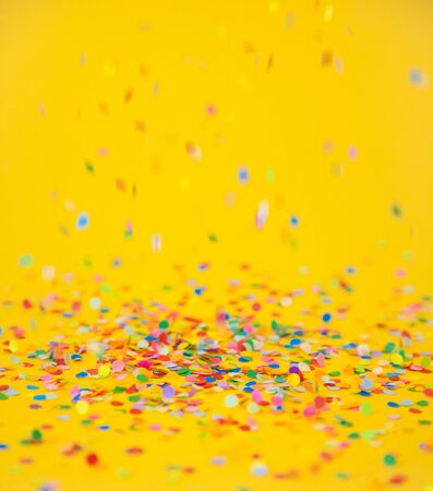 colourful sparlking confetti on yellow backgroundの写真素材
