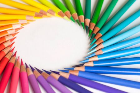 Crayons - colored pencil set loosely arranged on white background. Round frame.