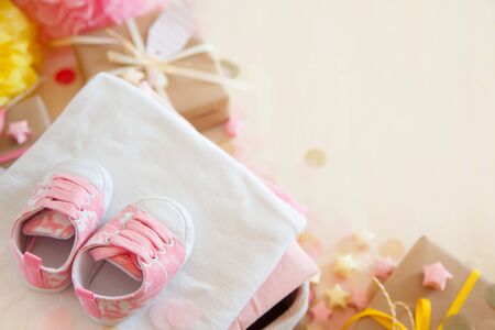 Gifts and pink decorations for girl baby shower indoors. close-up of baby shoesの写真素材