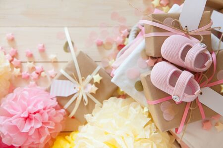 Gifts and pink decorations for girl baby shower indoors. close-up of baby shoesの写真素材