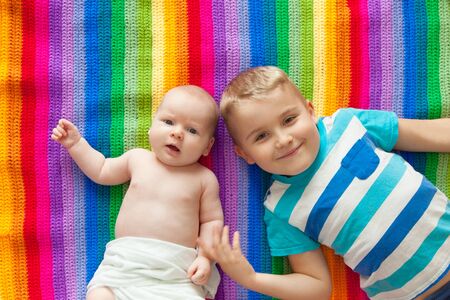Two boys brother lie on a striped rug. Baby 3 months. A boy of 6 years. Rainbow.の写真素材