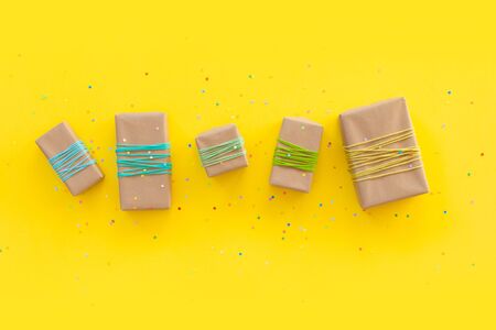 Colored gift boxes with colorful ribbons and pompon. Yellow background. Gifts for Christmas or a...
