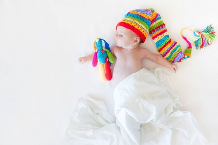 A baby one month is lying on a white background. Rainbow cap of the gnome.の写真素材
