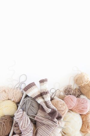 Neutral beige yarn for knitting is in the basket. Woolen warm socks. White background.の写真素材