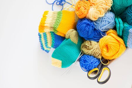 Knitting for children. Bright striped socks. Colored yarn. White background. Wicker basket.