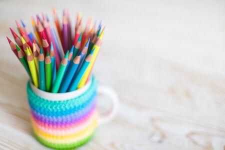 Stack of colored pencils in a glass on wooden background. Rainbow.の写真素材