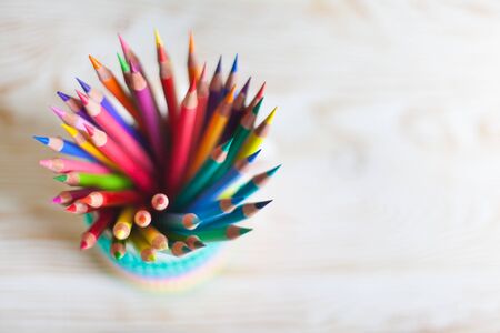 Stack of colored pencils in a glass on wooden background. Rainbow.の写真素材