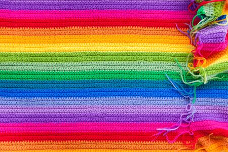 Crocheted crocheted color, bright, rainbow knitted fabric. Striped blanket. Female handicraft knitting.の写真素材