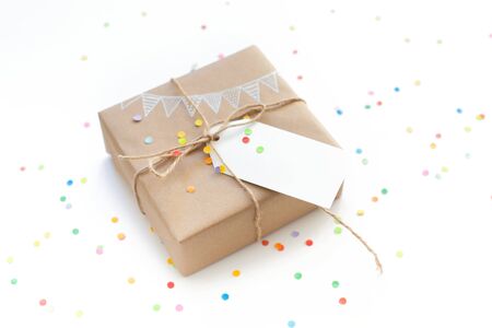 White gift box. Drawing of a white garland, flags. White background. Confetti.