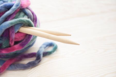 Knitted fabric of very thick yarn. A big tangle. The background is aged wood. Thick knitting needles.の写真素材