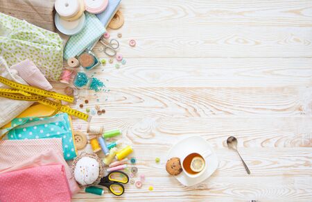 Many different rainbow materials for needlework and sewing. A girl / woman is drinking tea.