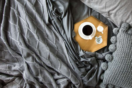 Morning breakfast in bed. Gray bedding. Golden tray in the nordic style. White cup with black coffee...