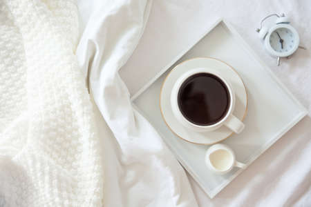 Morning breakfast in bed. White bedding. Golden tray in the nordic style. White cup with black...
