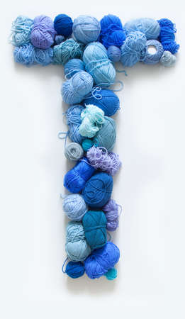 The letter T is made of multi-colored skeins and a ball of yarn. White background. Rainbow color gradient.の写真素材