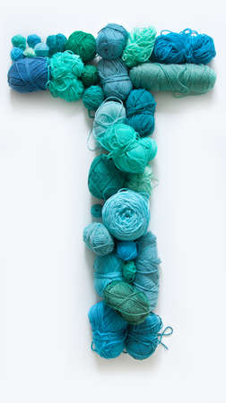 The letter T is made of multi-colored skeins and a ball of yarn. White background. Rainbow color gradient.の写真素材