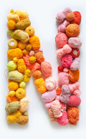 The letter N is made of multi-colored skeins and a ball of yarn. White background. Rainbow color gradient.の写真素材
