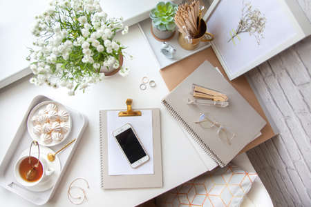 Flat lay, top view office table desk. Workspace with blank clip board, office supplies, pencil, telephone and cup of tea on white background.の写真素材