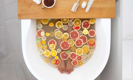 Top view orange, lemon, grapefruit slices and woman legs in bathtub.の写真素材