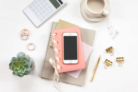 Minimal office desk table with stationery set, coffee cup, earphone and green plant in a pot.の写真素材