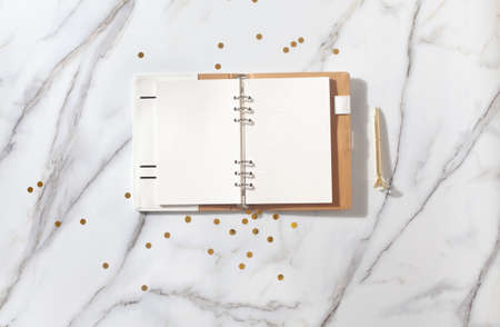 Notebook with empty pages for text, with pen, coffee cup, gift boxes, gold sparkles on white deskの写真素材