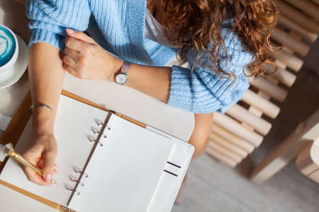 Young woman in blue warm sweater writing notes