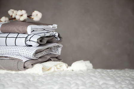 Stack of folded warm blankets with different design patterns and cotton branch on grey backgroundの写真素材