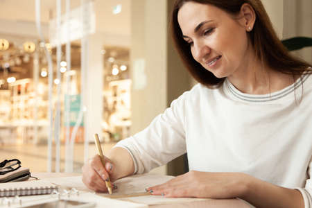 Young businesswoman in eyeglasses planning and writing down the daily schedule with in agenda