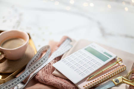 Top view of folded coral coloured lace and silk fabrics with tailoring tools near cup coffeeの写真素材