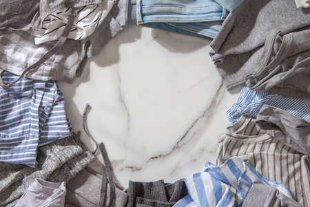 Frame made of clothing as pyjamas, undergarments, garments on a white marble background. Apparel sorting and decluttering. Concept of organic cotton clothing manufacturing. Nordic style. Copy space.の写真素材