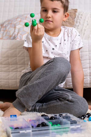 The boy collects from the constructor a model of an emerald molecule using the formula. Layout of...