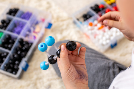 The boy collects a propane molecule model from the constructor using the formula. Layout of various particles. Young chemist and biologist. Home education concept.のeditorial素材