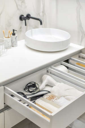 Bathroom under sink organizer drawers with neatly placed bath amenities and toiletries.の写真素材