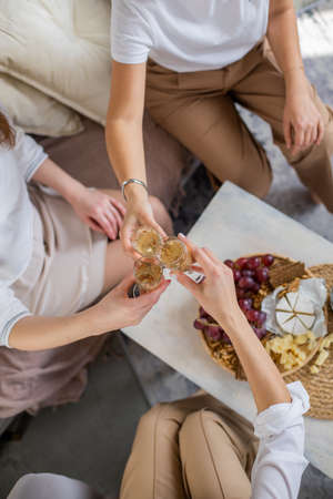 Three happy female friends drinking champagne cheers together laughing having positive emotion