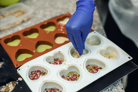 Closeup hands of confectioner applying berry sweet candy decor cooking matcha tea chocolateの写真素材