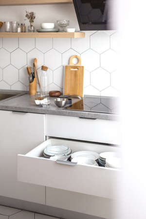 Comfortable white gray kitchen interior open box full of various crockery porcelain or glass platesの写真素材