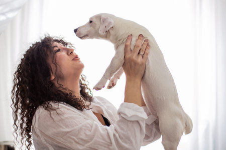 Happy curly brunette woman pet owner holding dog Jack Russell Terrier breed feeling love friendship