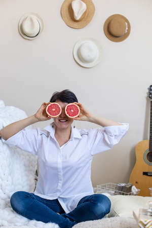 Funny vegan woman posing with half of fresh grapefruit laughing enjoying healthy lifestyle
